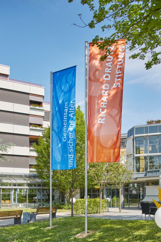 Bunte Fahnen vor moderner Einrichtung.