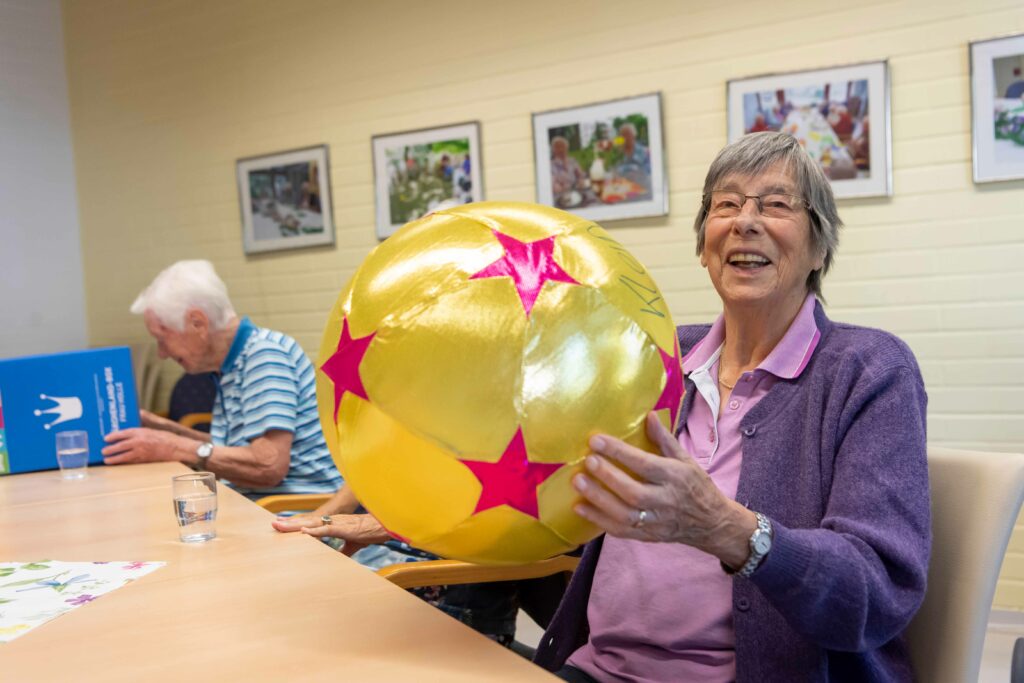 Seniorin lacht mit goldenem Ball.