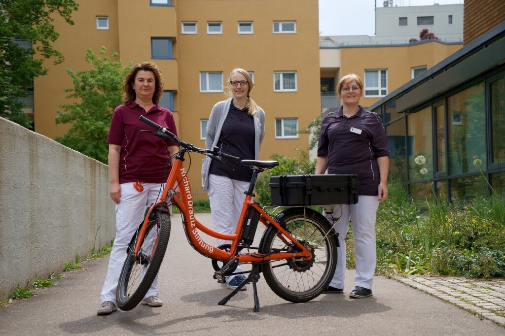 Drei Pflegerinnen, Lastenrad, Wohnanlage.