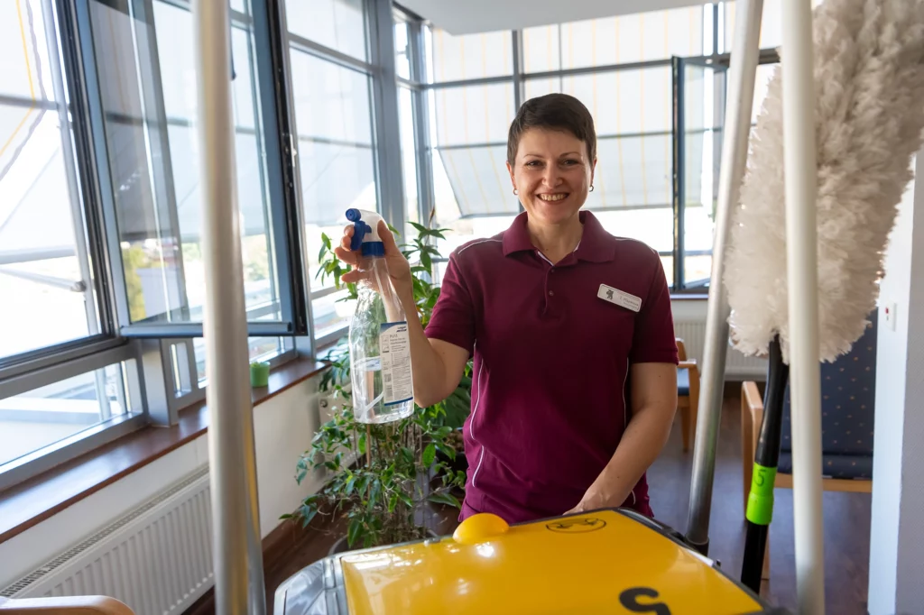 Freundliche Reinigungskraft mit Sprühflasche.